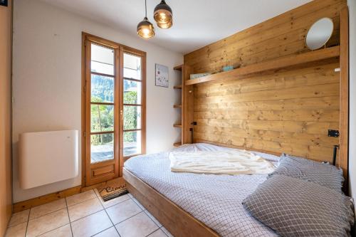 1 dormitorio con una pared de madera y 1 cama en L'Etoile Blanche - Appt vue montagne, en Flumet
