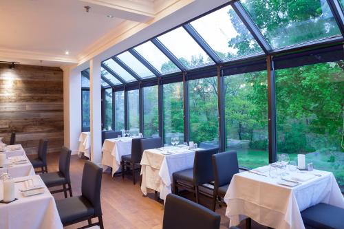 um restaurante com mesas e cadeiras e janelas grandes em L'Auberge Du Lac St-Pierre em Trois-Rivières