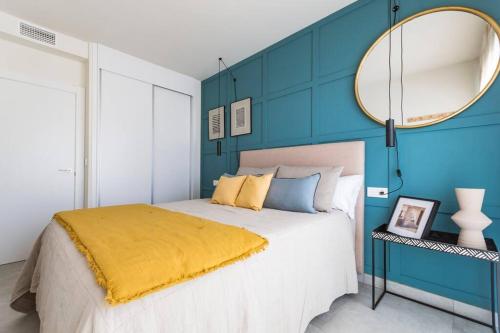 a bedroom with a blue wall with a bed and a mirror at Modern beach apartment Muchavista in Alicante