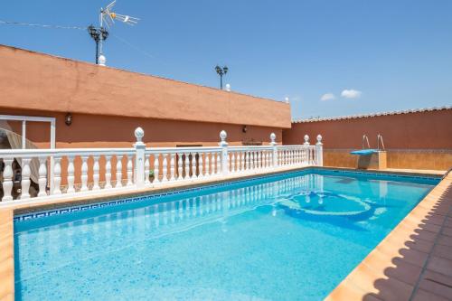 a swimming pool next to a building with a white fence at Villa Torres Motril in Motril