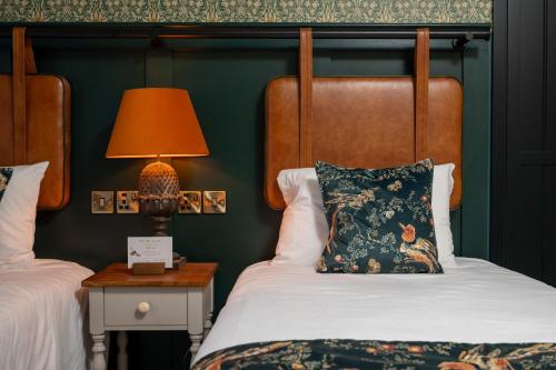 a bedroom with two beds and a lamp on a table at Ethorpe Hotel by Chef & Brewer Collection in Gerrards Cross
