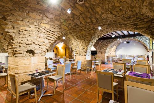 a restaurant with a stone wall and tables and chairs at Moulin de Vernègues Hôtel & Spa in Mallemort