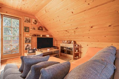 ポッチェトルテクにあるLog Cabin Chalets with Private Saunaのリビングルーム(青いソファ、テレビ付)
