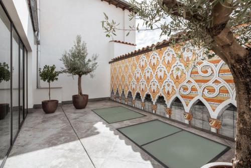 a courtyard with a tile wall with trees and mats at Áurea Toledo by Eurostars Hotel company in Toledo