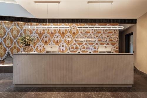 a lobby with a reception desk with a tile wall at Áurea Toledo by Eurostars Hotel company in Toledo