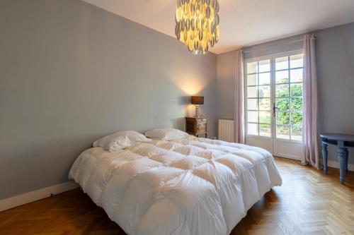 een slaapkamer met een wit bed en een kroonluchter bij Maison Carrosse - A 20min de Bordeaux in Martillac