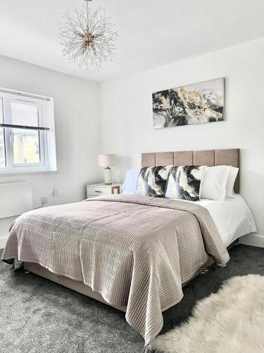a white bedroom with a large bed and a chandelier at 2 Bed apartment Sleeps 3 -Smart Tv -Private garden in Huddersfield