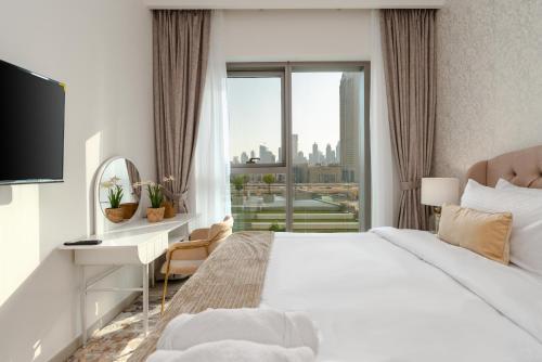 ein Hotelzimmer mit einem Bett, einem Schreibtisch und einem Fenster in der Unterkunft White Sage - Base to Top of Burj Khalifa Views in this New 2BR in Dubai