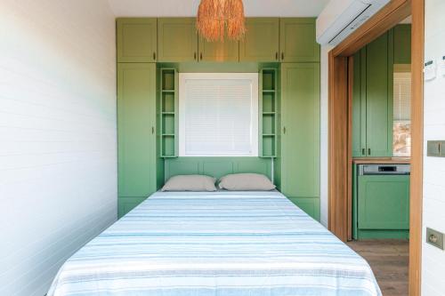 Bett in einem Zimmer mit grünen Schränken und einem Fenster in der Unterkunft Yomra Suites in Trabzon