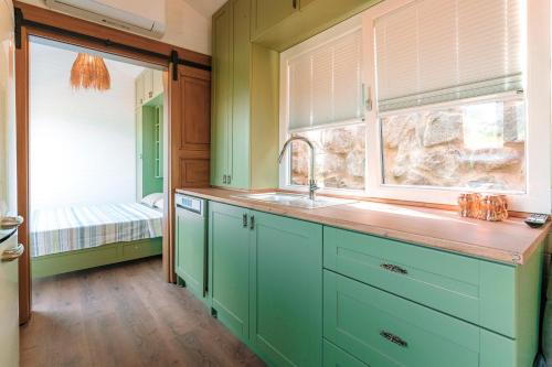 eine Küche mit grünen Schränken, einem Waschbecken und einem Fenster in der Unterkunft Yomra Suites in Trabzon