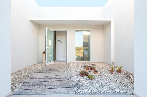 a white house with a courtyard with potted plants at Tenuta Quattro Volpi in Melendugno