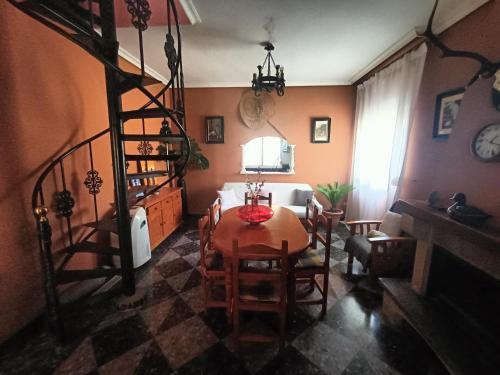 a living room with a table and a spiral staircase at Casa rural en el campo con animales, piscina y barbacoa in Almodóvar del Río