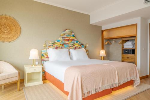 a bedroom with a large bed and a chair at Pestana Vila Lido Madeira Ocean Hotel in Funchal