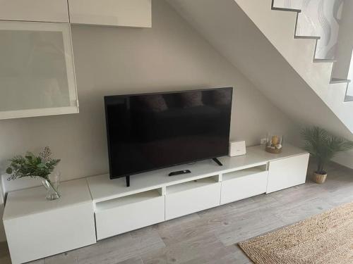 a flat screen tv sitting on a white cabinet in a living room at Duplex con piscina cerca del mar in Puertito de Güímar