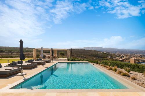 a pool with lounge chairs and a view of a city at Tholaria Villa in Chania Town
