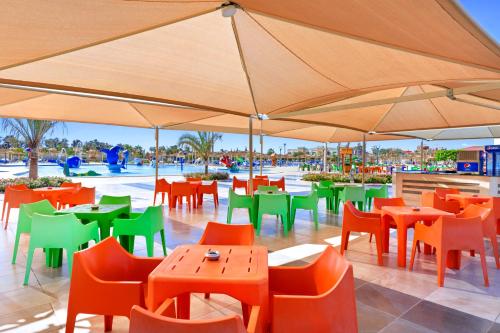 a restaurant with orange and green tables and chairs at Pickalbatros Aqua Park Sharm El Sheikh in Sharm El Sheikh