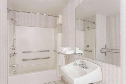 a bathroom with a sink and a tub and a mirror at Days Inn by Wyndham Phoenix West in Phoenix