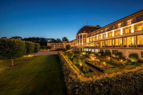 un edificio con un jardín delante de él por la noche en Parkhotel Bremen – ein Mitglied der Hommage Luxury Hotels Collection, en Bremen