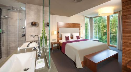 - une chambre d'hôtel avec un lit et une baignoire dans l'établissement Dorint Thermenhotel Freiburg, à Fribourg-en-Brisgau
