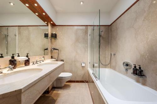 a bathroom with two sinks and a tub and a toilet at Parkhotel Bremen – ein Mitglied der Hommage Luxury Hotels Collection in Bremen