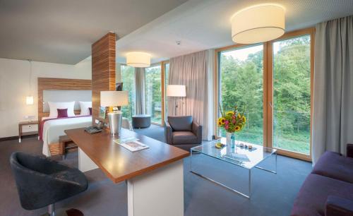 um quarto de hotel com um quarto, uma cama e uma secretária em Dorint Thermenhotel Freiburg em Friburgo em Brisgóvia