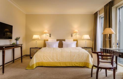 a bedroom with a bed and a table and chairs at Parkhotel Bremen – ein Mitglied der Hommage Luxury Hotels Collection in Bremen
