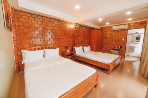 a bedroom with two beds and a brick wall at Chào Hotel Mũi Né in Mui Ne