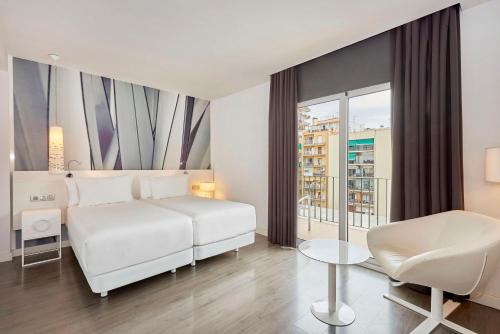 a white bedroom with a white bed and a chair at NH Barcelona Stadium in Barcelona