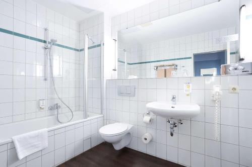 een badkamer met een toilet, een wastafel en een douche bij B&K Hotels in Vlotho