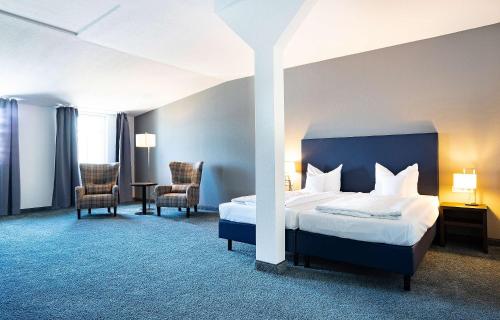 une chambre d'hôtel avec un lit et deux chaises dans l'établissement B&K Hotels, à Vlotho