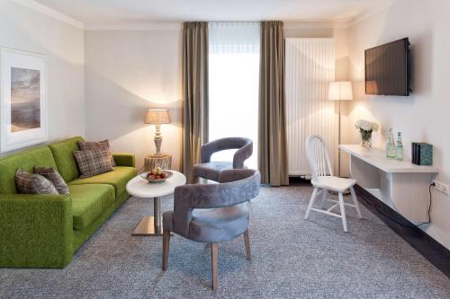 a living room with a green couch and a table at Dorint Resort Baltic Hills Usedom in Korswandt