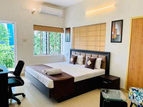 a bedroom with a bed and a chair and a window at Olive Serviced Apartments Salt Lake Kolkata in Kolkata