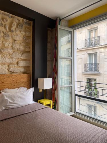 ein Schlafzimmer mit einem Bett und einem großen Fenster in der Unterkunft Hôtel Prince de Conti in Paris