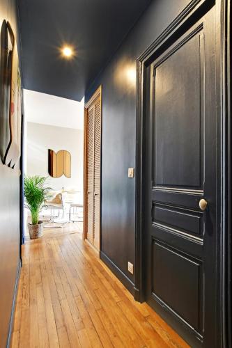 - un couloir avec une porte noire et du parquet dans l'établissement Luxury Cocon, à Boulogne-Billancourt