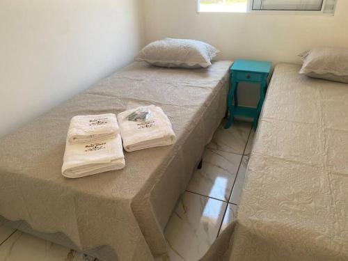 two beds in a room with towels on them at Apto Bela Vista 02 in Pôrto Ferreira