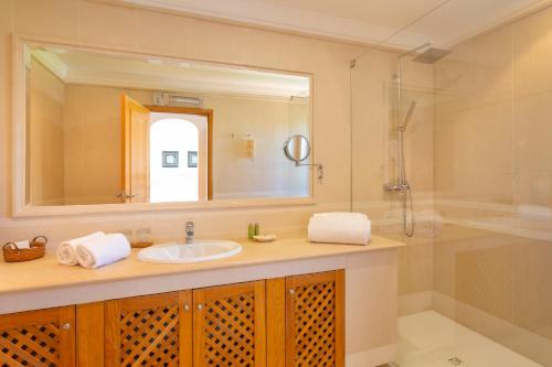 a bathroom with a sink and a shower and a mirror at Martinhal Quinta Family Resort in Quinta do Lago
