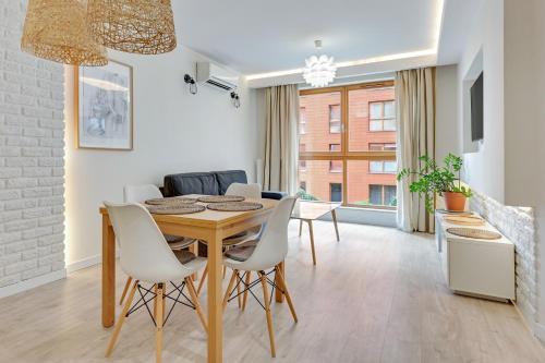 a dining room with a wooden table and white chairs at Downtown Apartments Riverside Aura Island in Gdańsk