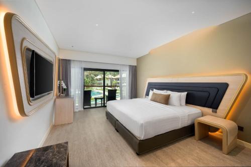 a bedroom with a large bed and a television at Amora Beach Resort Phuket in Bang Tao Beach