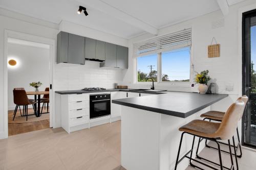 a kitchen with white cabinets and a black counter top at Haven at Rye by Ready Set Stay - BYO LINEN & TOWELS in Rye