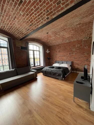 una camera da letto con pareti in mattoni, un letto e un divano di Loft Apartment by Letrent a Żyrardów