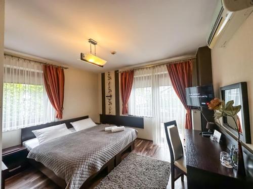 a bedroom with a bed and a desk and windows at Hotel Mieszko in Rzeszów