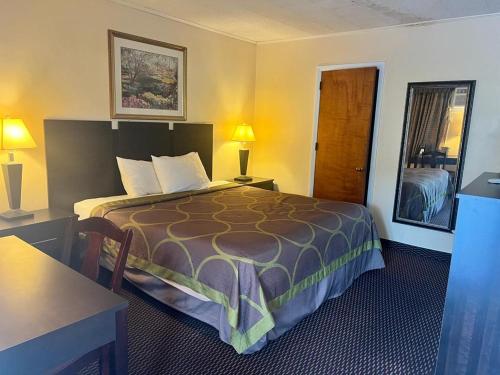 une chambre d'hôtel avec un lit, une table et des lampes dans l'établissement Budget Host Inn, à New Berlinville