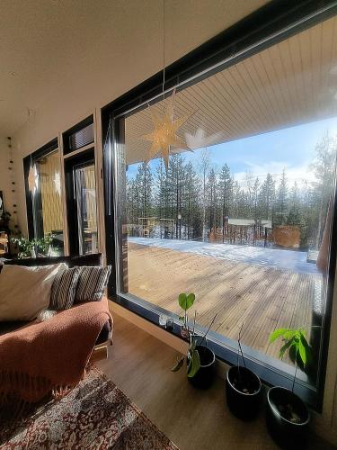 een woonkamer met een groot raam met potplanten bij Holiday Black Pearl in Rovaniemi