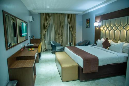 a hotel room with a large bed and a desk at Carlton Swiss Grand Hotel in Enugu