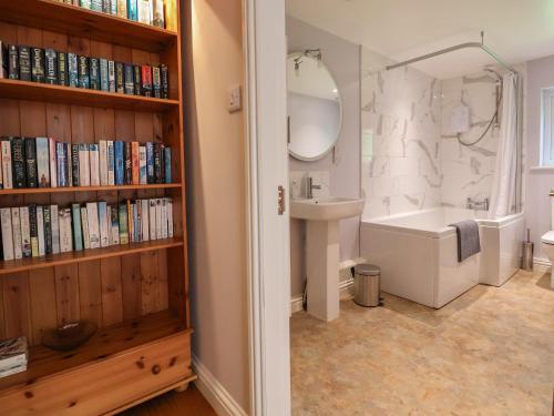 a bathroom with a sink and a toilet and a book shelf at Bramble Lodge in Northwich