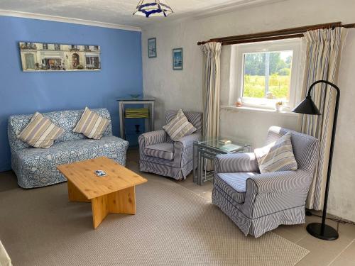 a living room with a couch and chairs and a table at Le petit gîte blanc, Langourla in Langourla