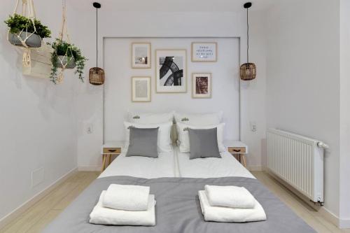 a white bedroom with a large bed with two pillows at Downtown Apartments Riverside Aura Island in Gdańsk
