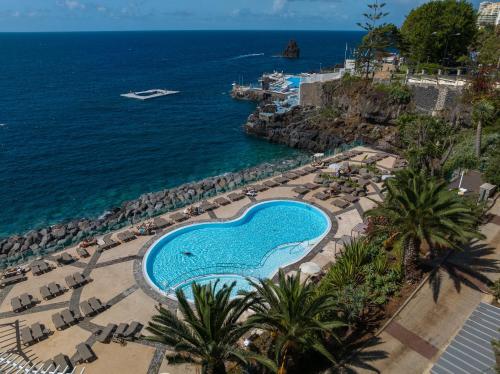 an aerial view of a swimming pool next to the ocean at Pestana Vila Lido Madeira Ocean Hotel in Funchal