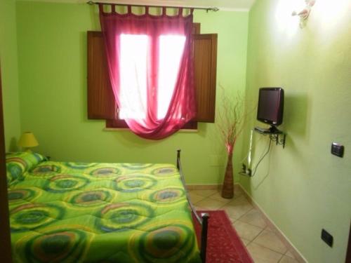 a bedroom with a bed and a window and a television at Agriturismo S´Aranada in Marrùbiu