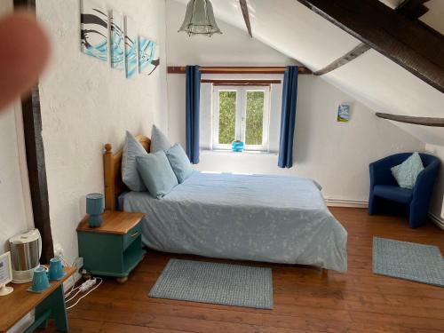 a bedroom with a bed with a blue chair and a window at La Vieille Boulangerie in Langourla